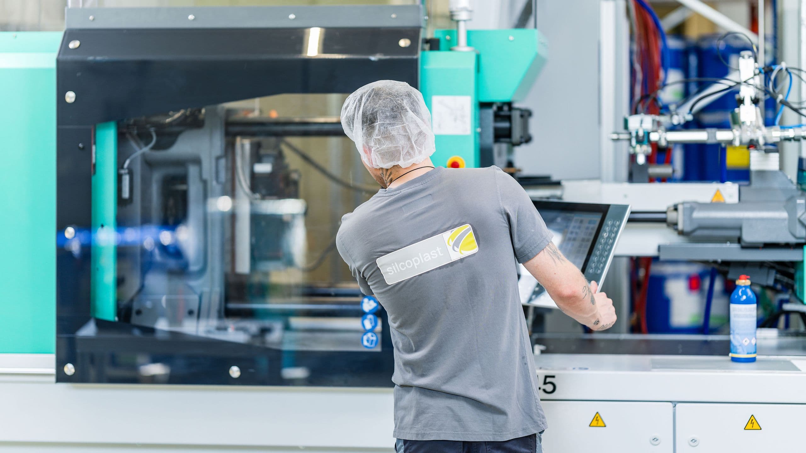 Mitarbeiter vor Maschine mit Silcoplast Logo